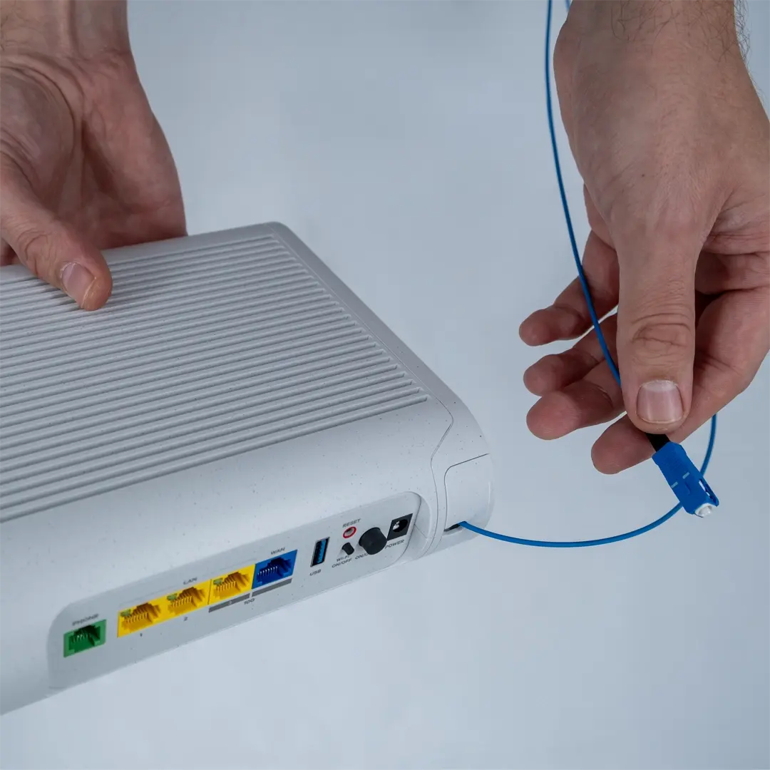 En person holder ruteren og viser den blå fiberkabelen som skal kobles til hjemmets fiberuttak.